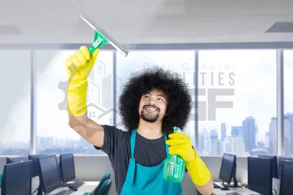 Persona con guantes limpiando los ventanales de una oficina
